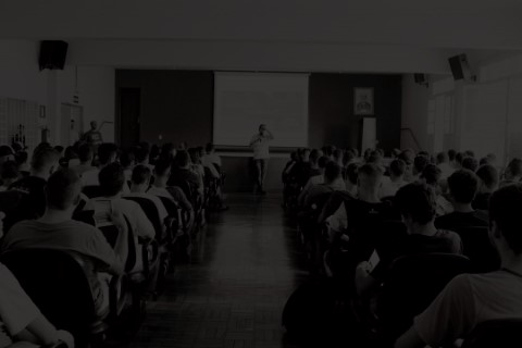 Foto de fundo, mostrando o auditório da FAPAM cheio.